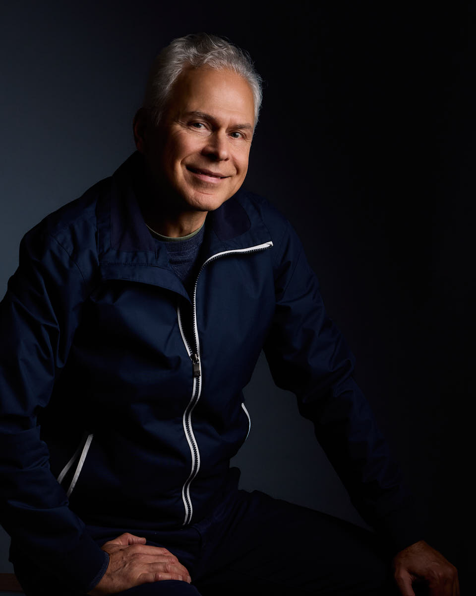 Självporträtt av Martin Ekwall, sittandes mot mörkblå bakgrund tittar in i kameran. För Photo for Brands